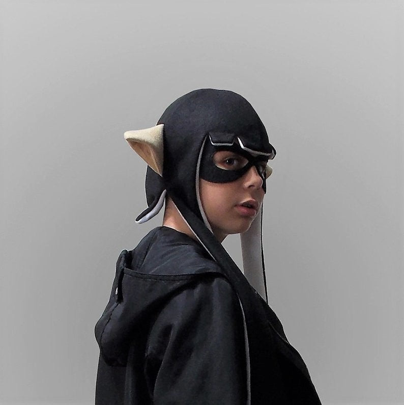 close-up of a young girl wearing a black Splatoon Inkling cosplay hat with color skin pointed ears, side profile view