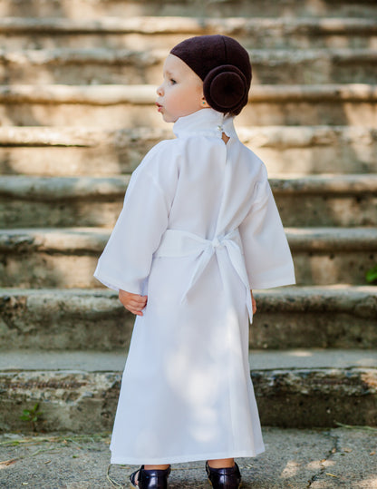 Back view of toddler in handmade Princess Leia kids costume — white robe dress with tied white belt and brown bun headpiece