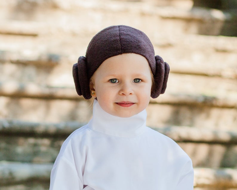 Close-up of toddler wearing handmade Princess Leia brown bun headpiece with white turtleneck costume