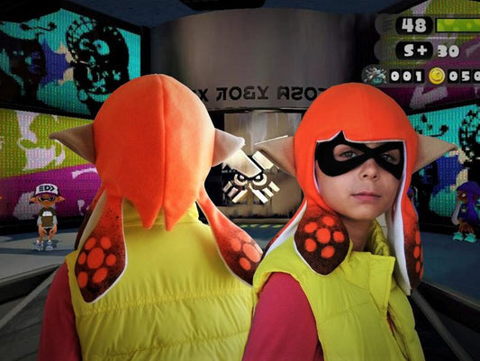 Child wearing orange Splatoon 2 Inkling cosplay hat with tentacles and pointed ears, black mask, Splatoon game background